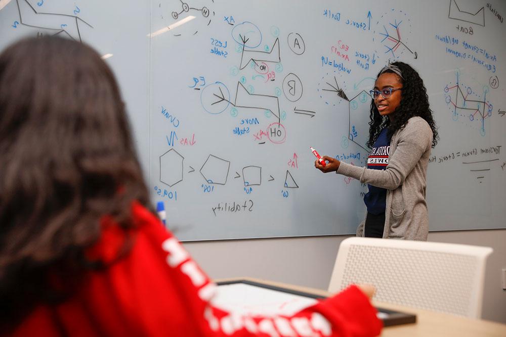 tutor wokring chemistry on a whiteboard